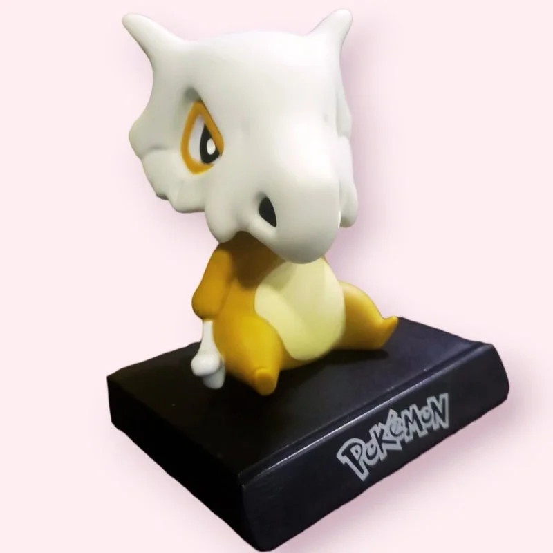 Soporte celular Cubone Pokémon blanco y amarillo sobre base negra
